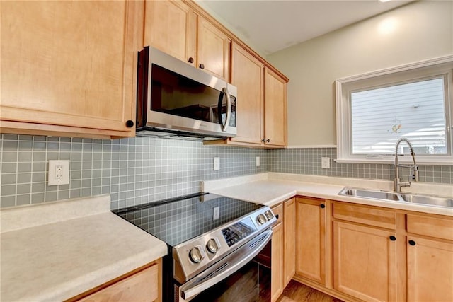 kitchen with appliances with stainless steel finishes, light countertops, a sink, and tasteful backsplash