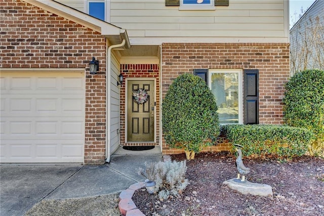 entrance to property featuring a garage and brick siding