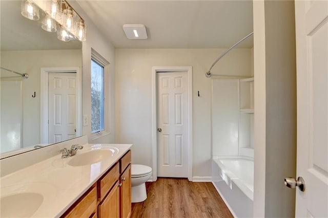 bathroom with wood finished floors, a sink, toilet, and double vanity