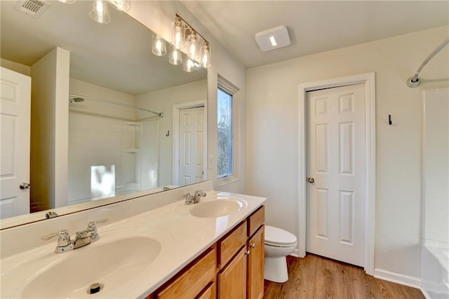 bathroom with double vanity, visible vents, a sink, and wood finished floors