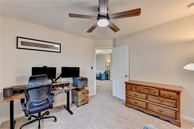 office space featuring baseboards, a ceiling fan, and light colored carpet