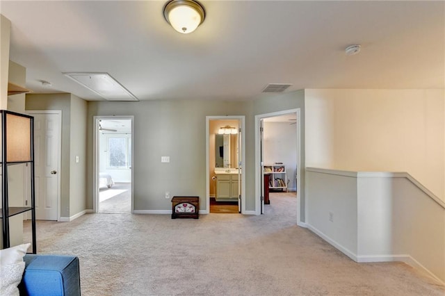 interior space with attic access, visible vents, baseboards, light colored carpet, and a sink