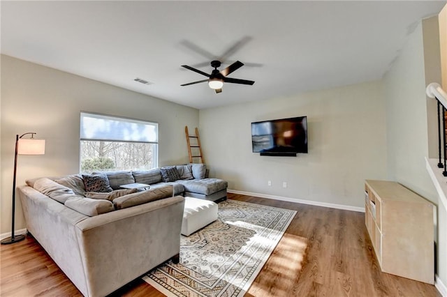 living room with light wood finished floors, baseboards, visible vents, and a ceiling fan