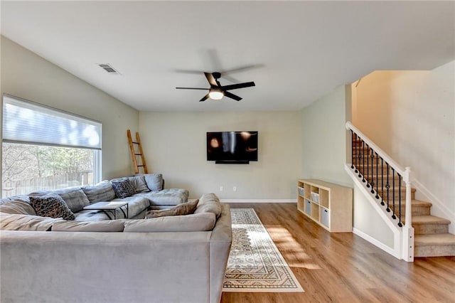 living area featuring stairs, wood finished floors, visible vents, and baseboards