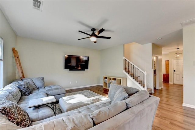 living area with visible vents, baseboards, a ceiling fan, light wood-style flooring, and stairs