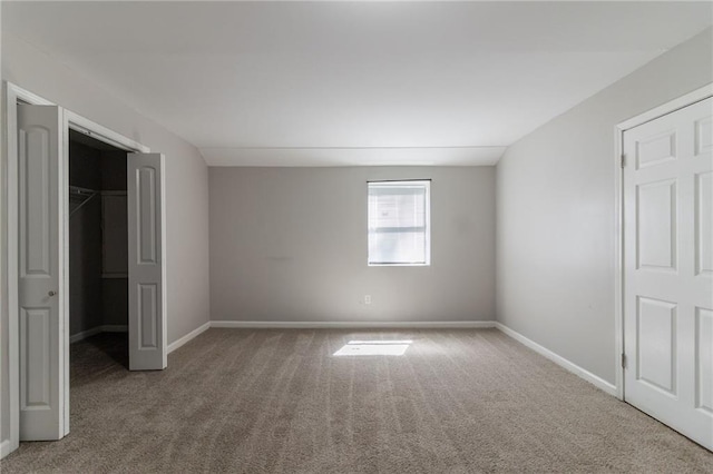 unfurnished bedroom featuring baseboards, carpet, a closet, and a walk in closet