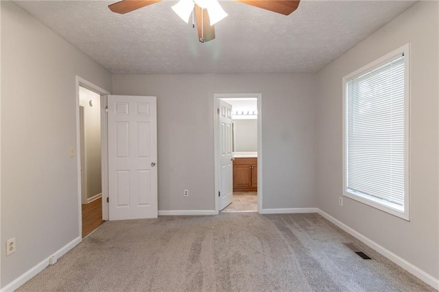 unfurnished bedroom with baseboards, light carpet, and a textured ceiling