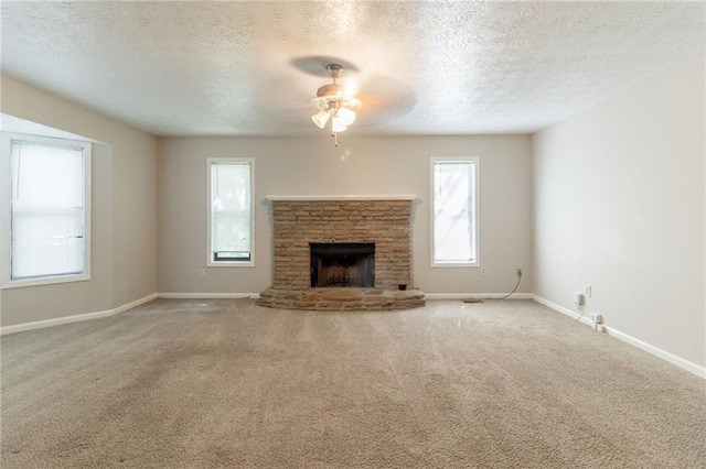 unfurnished living room with a stone fireplace, a ceiling fan, a textured ceiling, and carpet floors