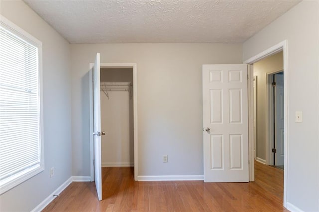 unfurnished bedroom with a closet, multiple windows, and light wood-type flooring