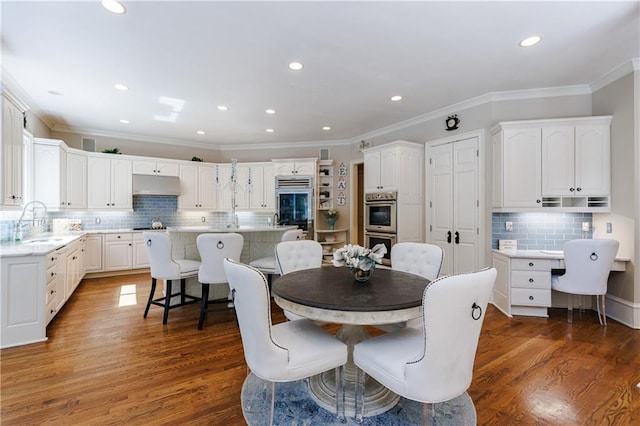 dining room with hardwood / wood-style flooring, sink, and ornamental molding