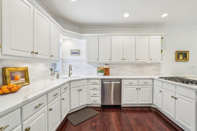 kitchen featuring stainless steel appliances, a sink, dark wood-type flooring, white cabinets, and crown molding