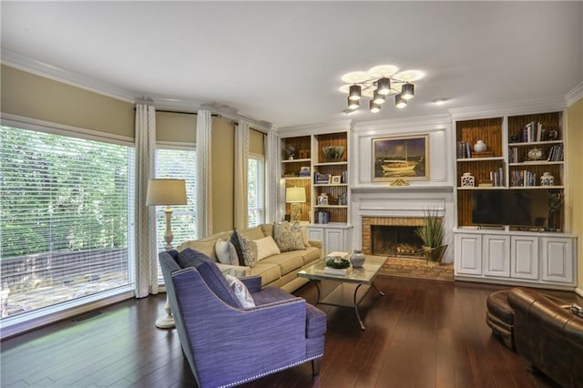 living area with ornamental molding, dark wood-style floors, a fireplace, a chandelier, and built in shelves