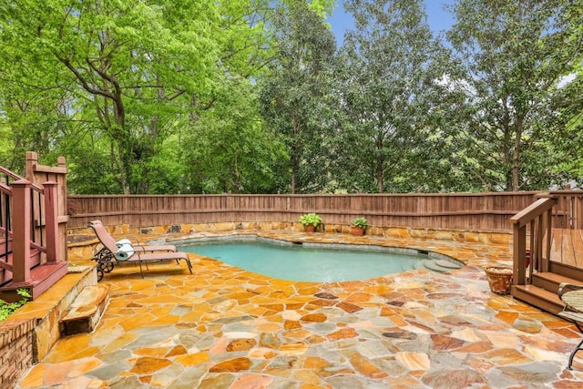 view of pool featuring a fenced backyard, a patio area, and view of wooded area