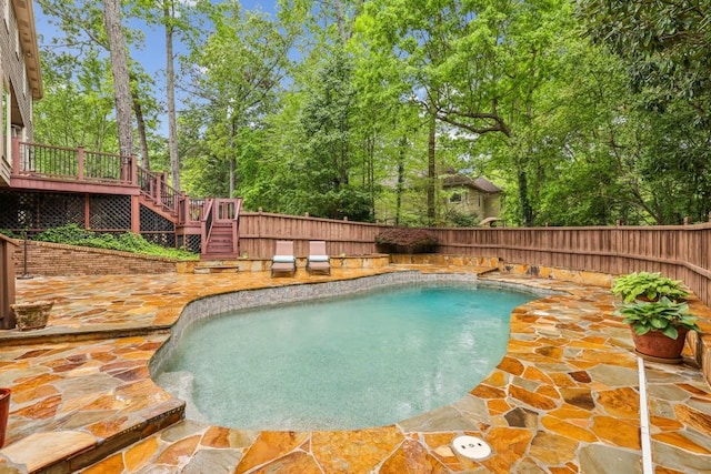 view of swimming pool with stairs, a fenced backyard, a patio, a wooden deck, and view of wooded area