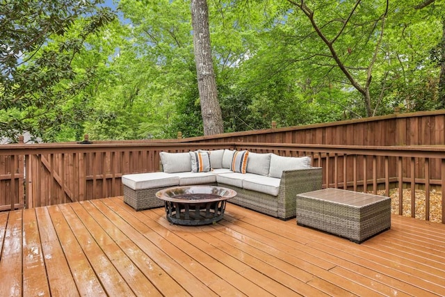wooden deck with an outdoor living space with a fire pit, view of scattered trees, and fence