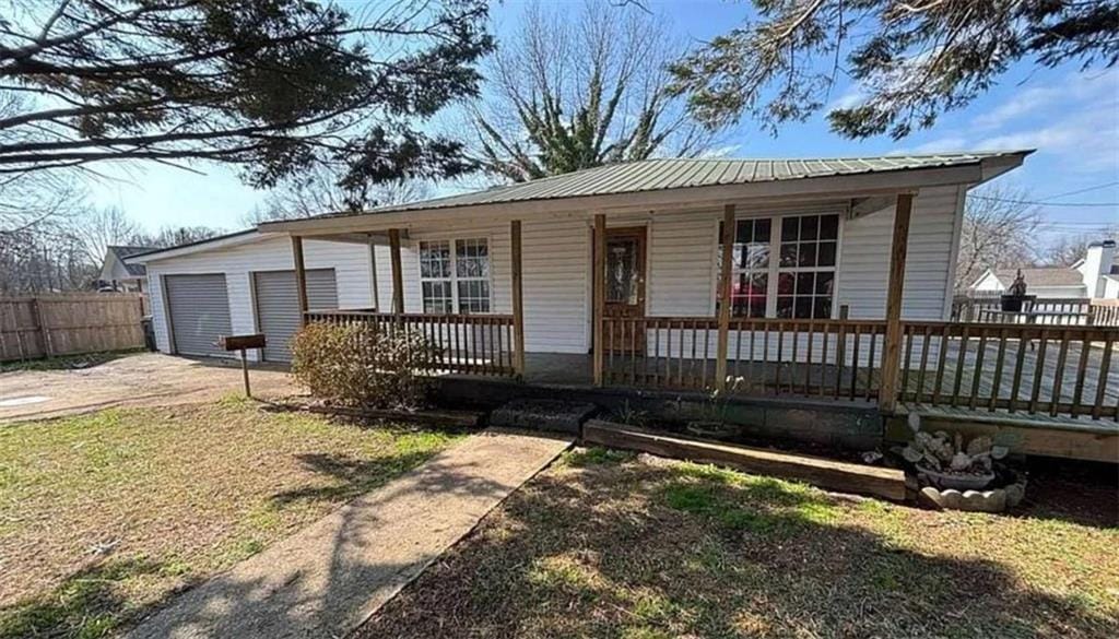 6205 Helen St, Lula, GA 30554 - single story home with covered porch, metal roof, concrete driveway, and an attached garage