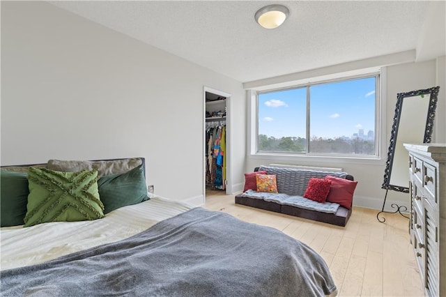 bedroom with baseboards, light wood-style flooring, and a closet