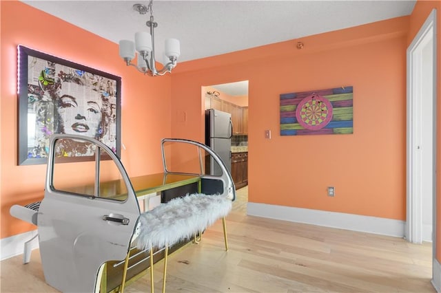 interior space with baseboards, an inviting chandelier, and light wood-style flooring