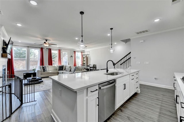 kitchen with decorative light fixtures, white cabinetry, dishwasher, sink, and a center island with sink