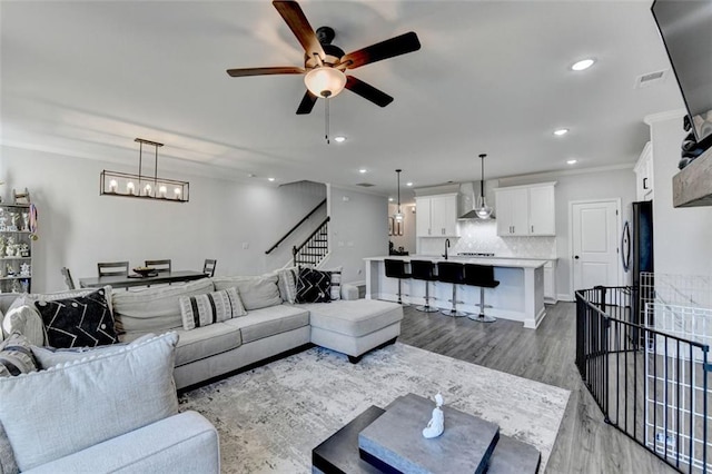 living room with crown molding, light hardwood / wood-style flooring, and ceiling fan with notable chandelier