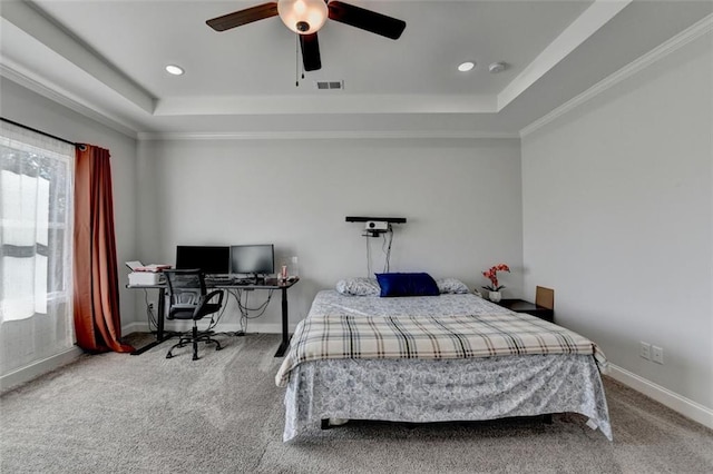 carpeted bedroom with a raised ceiling, ornamental molding, and ceiling fan