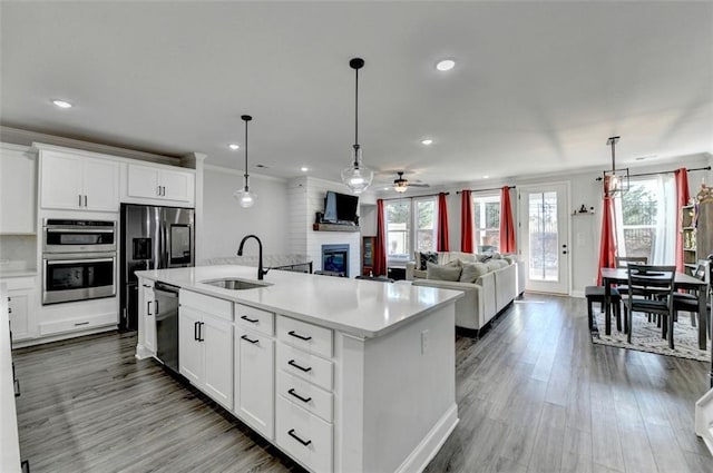 kitchen with white cabinetry, sink, stainless steel appliances, and a center island with sink