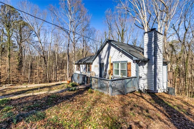 view of property exterior with a chimney and central AC