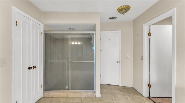 bathroom featuring a shower with shower door and tile patterned flooring