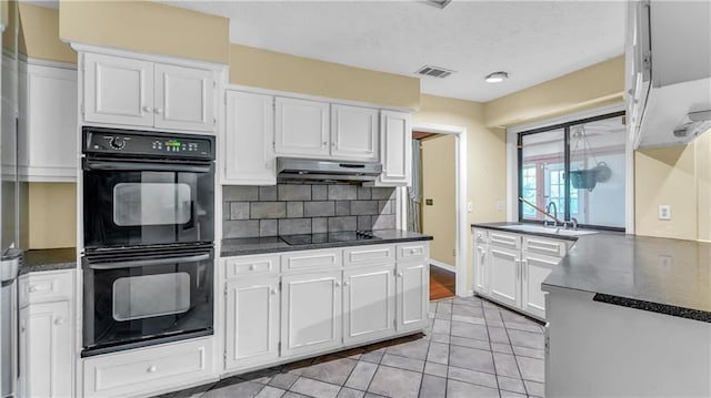 kitchen with decorative backsplash, white cabinets, black appliances, range hood, and sink