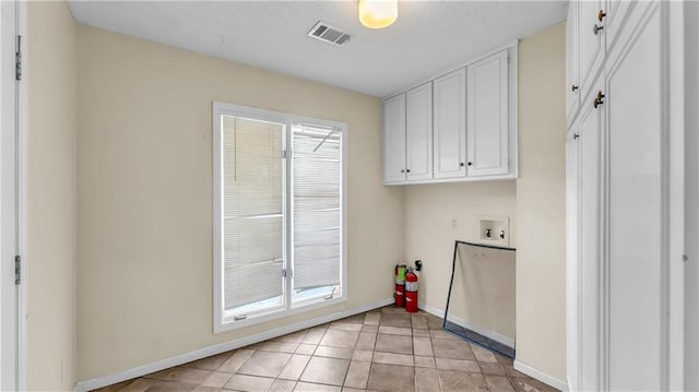 clothes washing area with hookup for a washing machine, cabinets, and light tile patterned floors