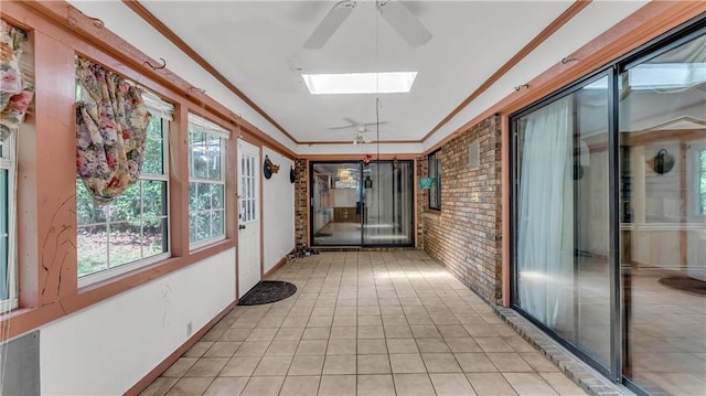 corridor featuring crown molding, a skylight, and brick wall