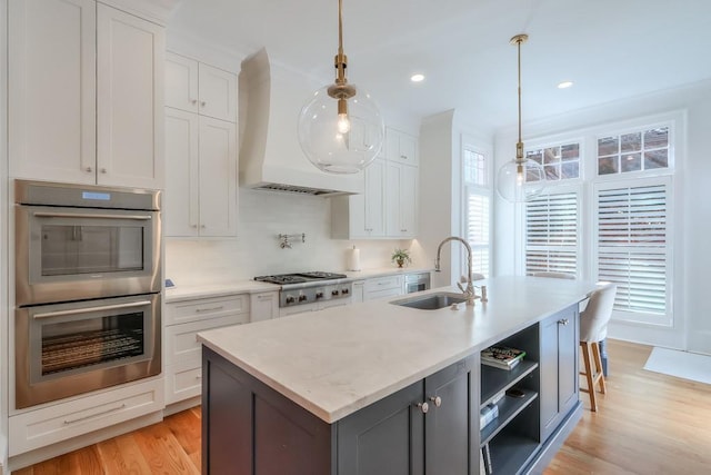 235 Founders Mill Ct, Roswell, GA 30075 - kitchen featuring appliances with stainless steel finishes, light wood finished floors, white cabinetry, a center island with sink, and decorative light fixtures