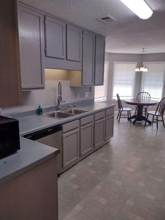 kitchen featuring visible vents, a sink, a textured ceiling, gray cabinets, and light floors