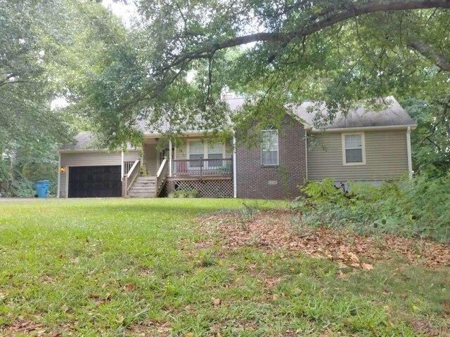 ranch-style house featuring a front yard, an attached garage, and covered porch