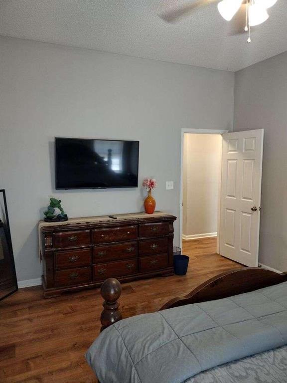 bedroom featuring ceiling fan, dark wood-style flooring, and baseboards
