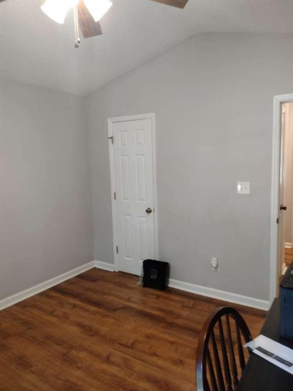 interior space with wood finished floors, ceiling fan, baseboards, and lofted ceiling