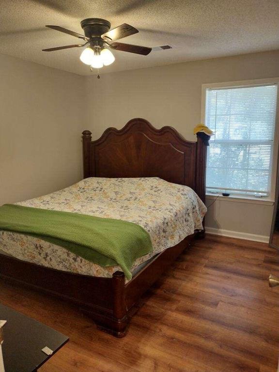 bedroom with ceiling fan, baseboards, and wood finished floors
