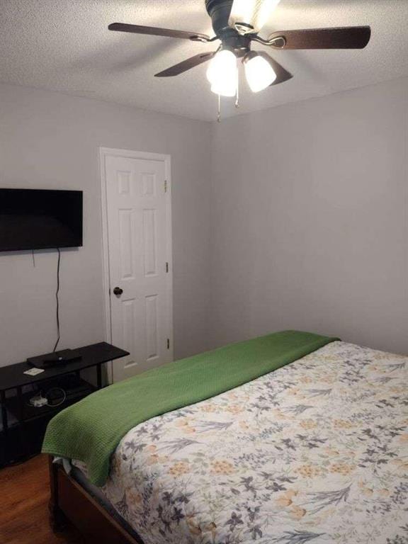 bedroom with dark wood-type flooring, a textured ceiling, and a ceiling fan