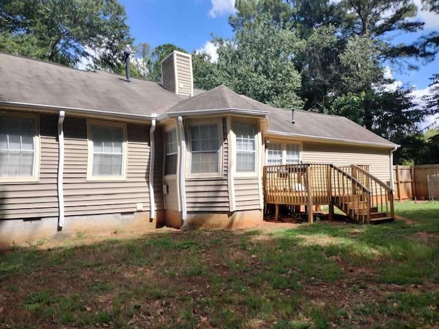 rear view of property with a chimney, crawl space, a wooden deck, fence, and a lawn