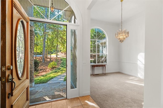 foyer entrance with light carpet, ornamental molding, and a notable chandelier