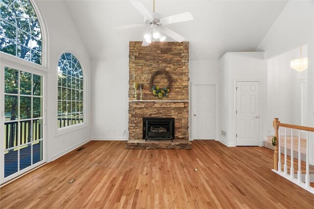 unfurnished living room with ceiling fan, a fireplace, high vaulted ceiling, and light wood-type flooring