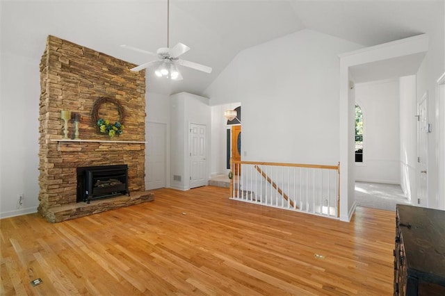 unfurnished living room featuring ceiling fan, light hardwood / wood-style floors, a stone fireplace, and high vaulted ceiling