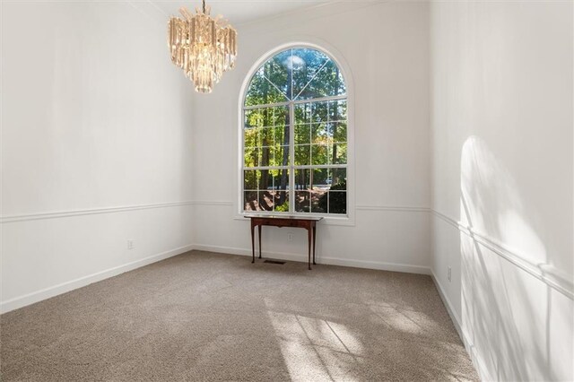 spare room with carpet floors and a notable chandelier