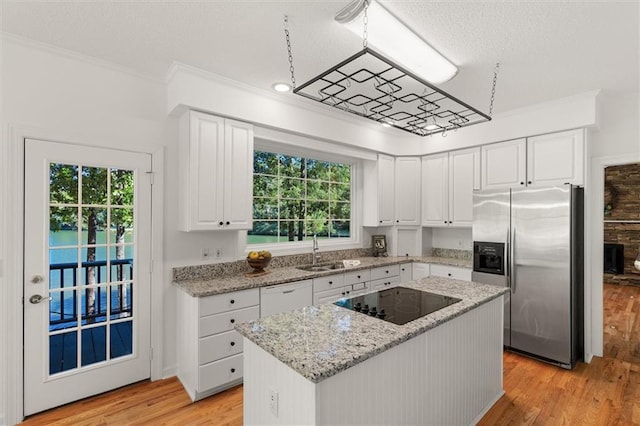 kitchen with stainless steel fridge, light wood-type flooring, black electric stovetop, a center island, and white cabinetry