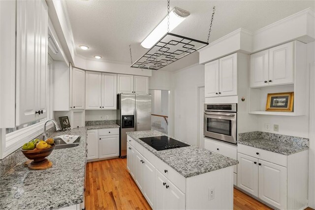 kitchen featuring white cabinets, sink, light wood-type flooring, a kitchen island, and stainless steel appliances