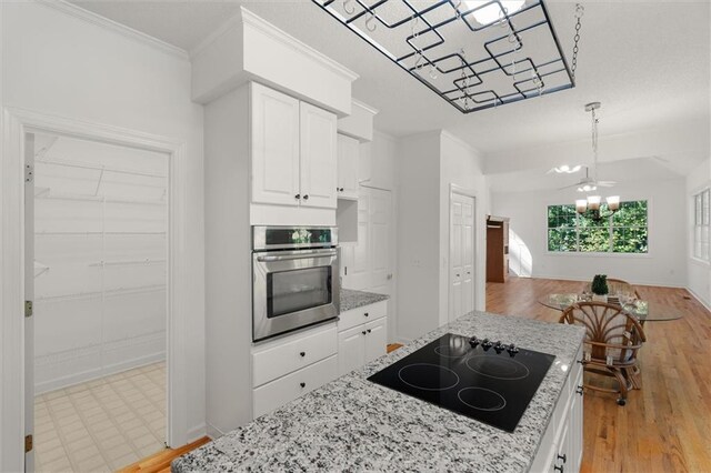 kitchen featuring white cabinetry, an inviting chandelier, light hardwood / wood-style flooring, oven, and black electric cooktop