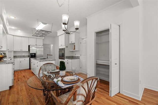 dining room featuring sink, light hardwood / wood-style flooring, crown molding, and a notable chandelier