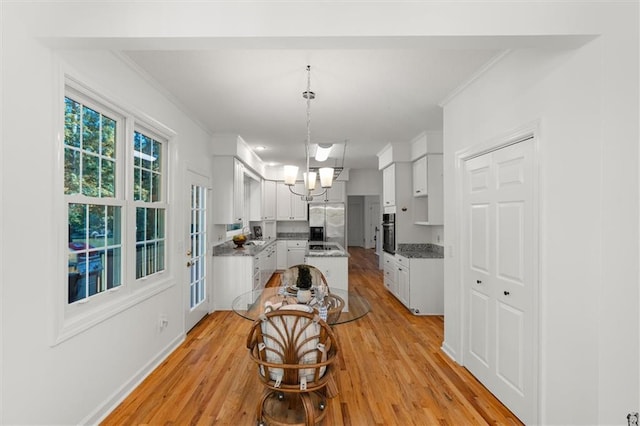 dining space featuring light hardwood / wood-style flooring, an inviting chandelier, and ornamental molding