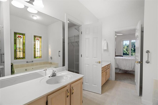 bathroom with tile patterned flooring, a bath, and vanity