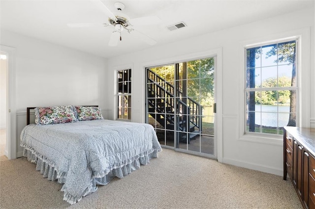 bedroom with ceiling fan, access to exterior, light carpet, and multiple windows